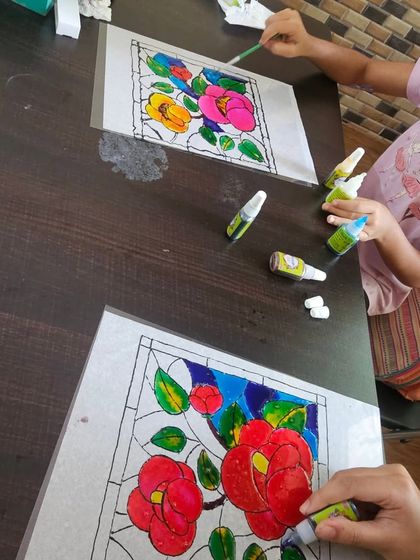 Two students working side-by-side on their glass painting projects, each creating a unique and beautiful piece.