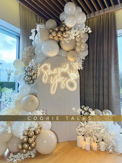 A breathtaking moment for a beautiful promise. We designed this elegant 'She Said Yes' engagement party setup with a clean, all-white theme, accented with gold balloons, soft lighting, and a custom neon sign to celebrate the special occasion.