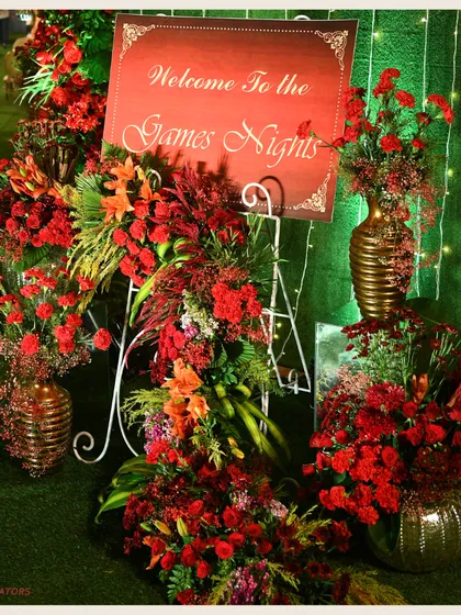 A personalized welcome to the Games Night. The sign is surrounded by lush red floral arrangements, setting a tone of sophisticated fun for the evening's festivities.