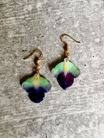 These beautiful earrings are made from real orchid petals. I carefully preserved the delicate flower to capture its stunning green and purple gradient, creating a piece of wearable nature.