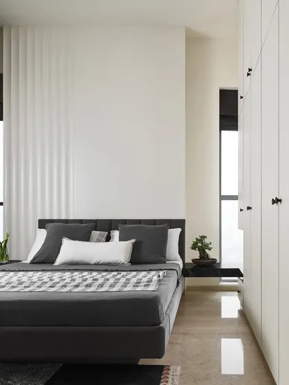 A view of the Slate Bedroom showing the interplay between the dark floating bed, the white handle-less wardrobes, and the cantilevered bedside table. The design is a study in contrasts and minimalist forms.