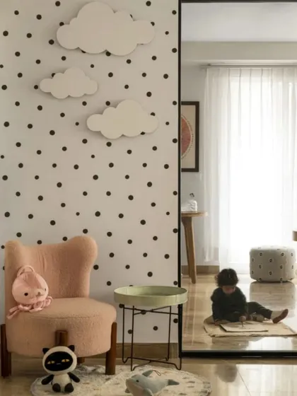 This cozy nook was designed for quiet play. A child-sized pink armchair is set against a wall with a simple polka-dot pattern and cloud-shaped appliques, creating a dreamy and imaginative corner.