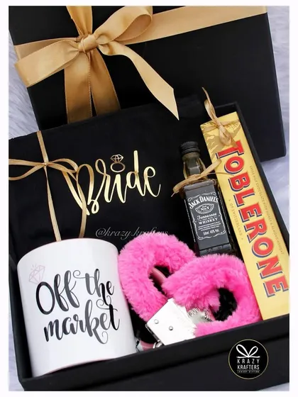 A naughty and nice hamper for the bride who is 'Off the Market'. This fun box includes a custom mug, a mini bottle of Jack Daniel's, and some playful accessories like pink fuzzy handcuffs.