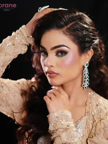 This pose highlights the dramatic earrings and the shimmering, glamorous makeup.