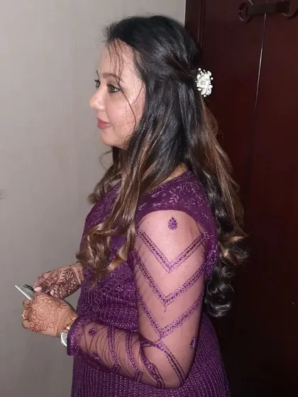 A side view of this party-ready look. The soft curls and simple hair accessory add a touch of elegance to her purple evening gown.