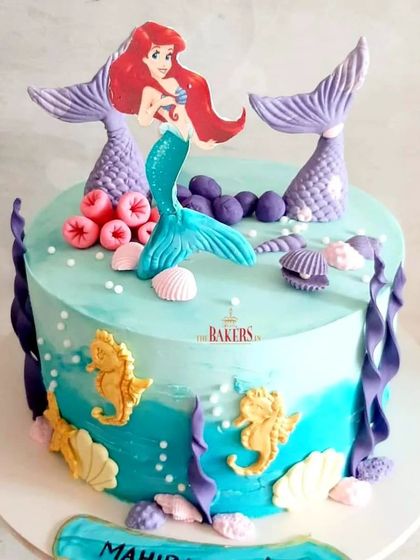 A gluten-free blue mermaid cake for a 4-year-old's birthday. This no-fondant cake is decorated with mermaid tails, seashells, and seahorses, creating a beautiful underwater scene.
