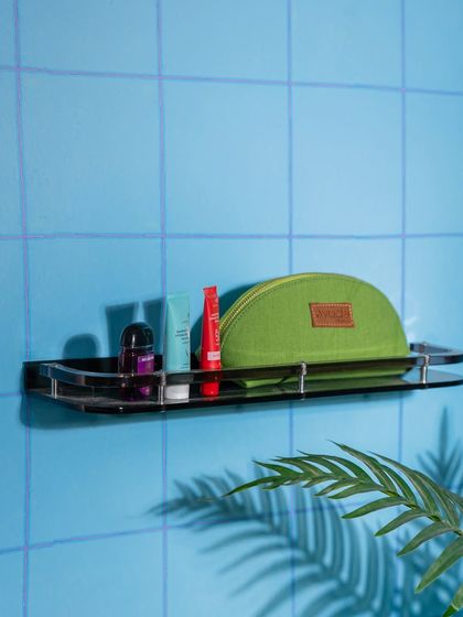 A green pouch and other toiletries on a bathroom shelf. This is a practical, in-context shot that shows the product's use case.