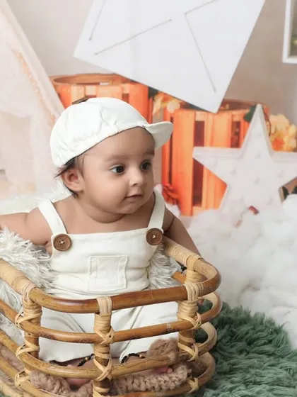 This little one is sitting up in a basket, surrounded by soft white clouds. This setup is ideal for babies around the 3-month mark, capturing their adorable expressions in a safe and cozy environment.
