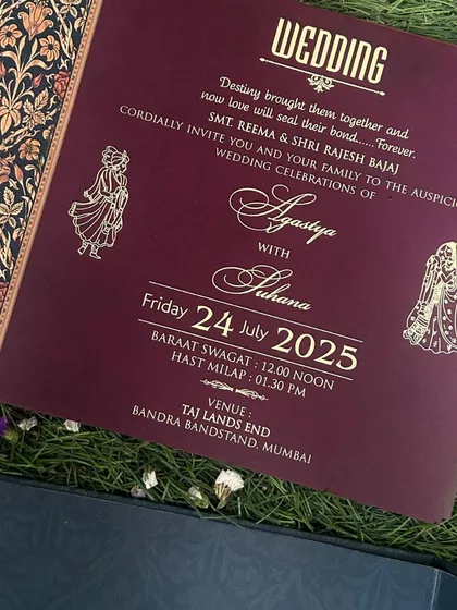 A wedding insert with a rich maroon background and elegant gold script, featuring a traditional floral border on the side.