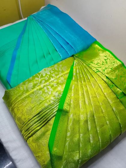 Let your silk sarees come out of the wardrobe. This image shows two vibrant sarees, a blue and a green, both pleated and ready to be enjoyed.