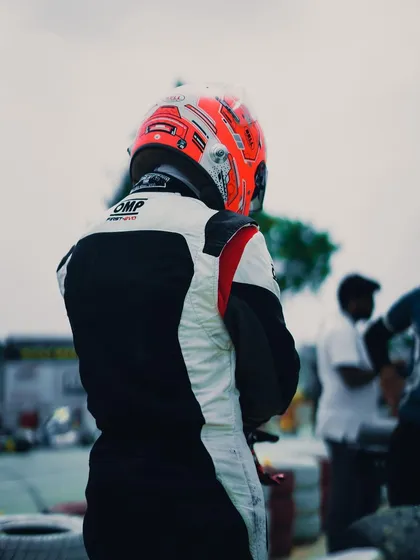 A driver stands in the pit area, contemplating the race.