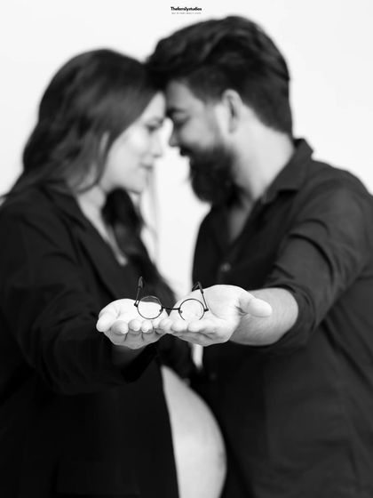 A close-up version of the couple holding the tiny glasses. This intimate, modern portrait focuses on the detail and the couple's connection, making it a perfect pregnancy announcement photo.