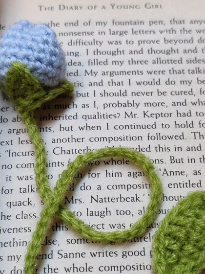 A close-up of my light blue tulip bookmark, shown inside "The Diary of a Young Girl". The design features a long stem that slips between the pages, with the flower peeking out from the top.