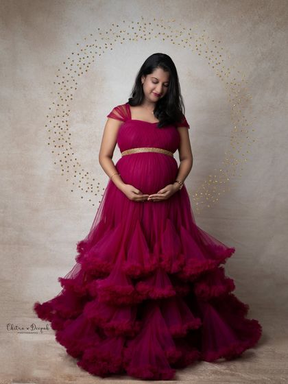A serene moment in magenta. The mom-to-be looks down at her bump, framed by a sparkling gold halo, creating a peaceful and loving portrait.