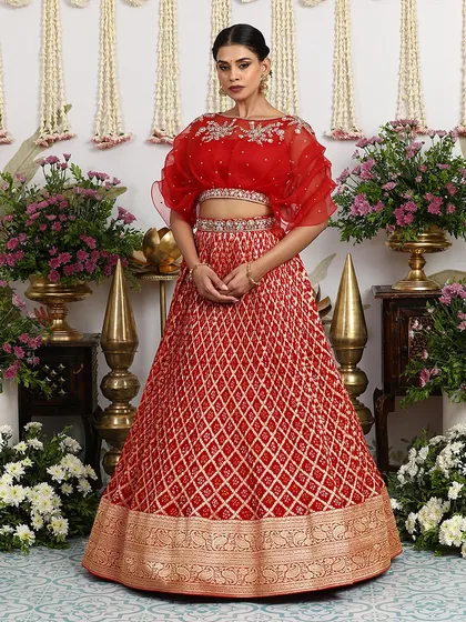 The full view of the red Bandhani lehenga, showcasing the intricate embroidery and the unique silhouette of the cape blouse.