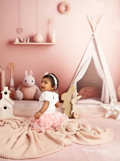 A wide view of the pink boho dreamland. This shot showcases the full studio setup, with a teepee, stuffed bunnies, and other props that create a magical world for a toddler.
