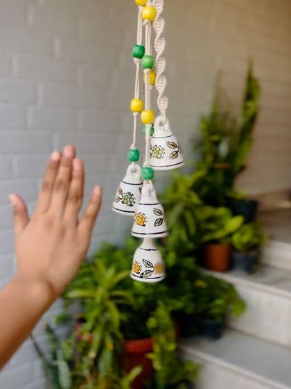 A close-up of our 'Symphony Chimes' in the 'Amaltas' variant, showing the beautiful details of the hand-painted ceramic bells and colorful wooden beads. Perfect for adding a touch of nature to your home.