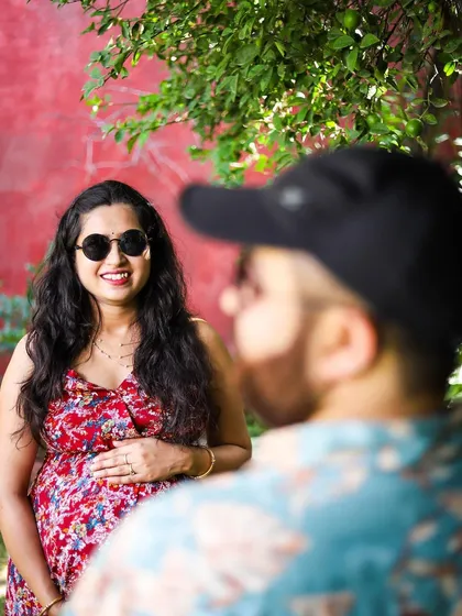 We love capturing candid interactions. This over-the-shoulder shot creates a personal, intimate perspective, as if you are seeing the moment through the partner's eyes. It highlights the genuine smiles and connection that make a couple's maternity session special.