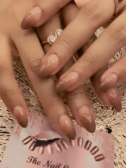 A moody and sophisticated ombre on long, almond-shaped nails. This set features a beautiful gradient from a sheer nude base to a deep brown at the tips.
