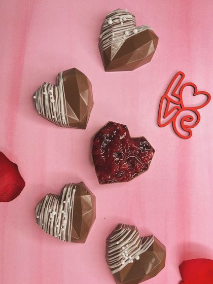 Love is sweet, and our heart-shaped chocolates make it even sweeter. These geometric chocolate hearts, some filled with jam and others drizzled with white chocolate, are perfect for celebrating Valentine's Day, anniversaries, or just because.