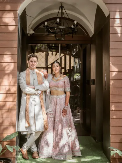A classic and elegant portrait of the couple standing in a stylish doorway. Their coordinated pastel outfits and confident poses create a sophisticated and timeless image.