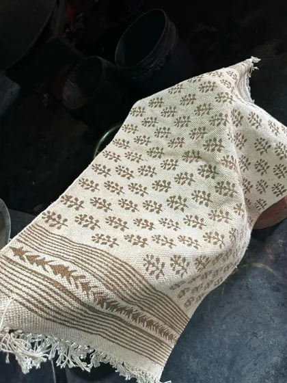 A close-up of the Dabu printed rug before dyeing. You can see the delicate leaf and border patterns printed in mud, which will resist the indigo dye.
