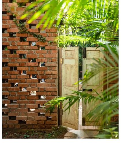 A light-colored vintage door set against a perforated brick wall, or 'jaali'. This combination plays with texture, light, and color, creating a beautiful and functional garden entrance.
