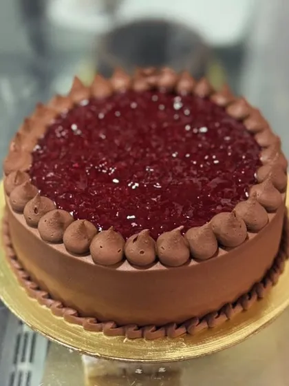 A delicious chocolate raspberry cake, featuring rich chocolate frosting and a glossy raspberry topping.