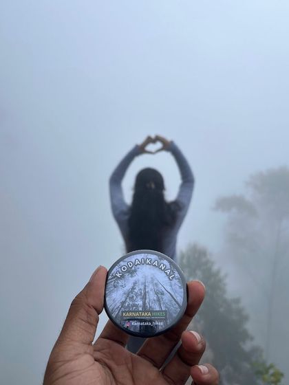 A creative shot of our Kodaikanal badge with a trekker making a heart shape in the misty background.