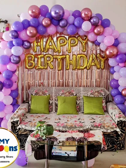 A simple yet elegant "Happy Birthday" setup for a home celebration. The purple and gold balloon arch frames the living room sofa, creating a festive focal point.