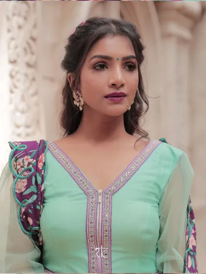 A portrait highlighting the modern V-neck design with a zipper on the turquoise peplum blouse, a blend of contemporary style and ethnic grace.