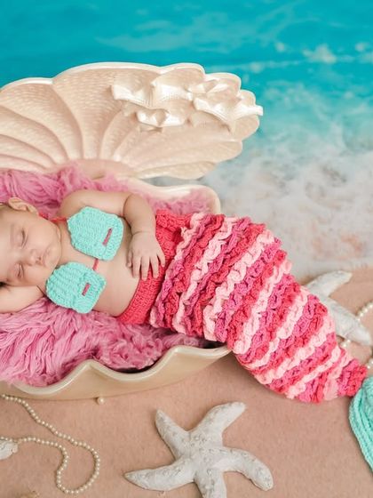 The little mermaid dreams peacefully. This angle captures the beautiful textures of the crocheted tail and the serene expression of the sleeping newborn.