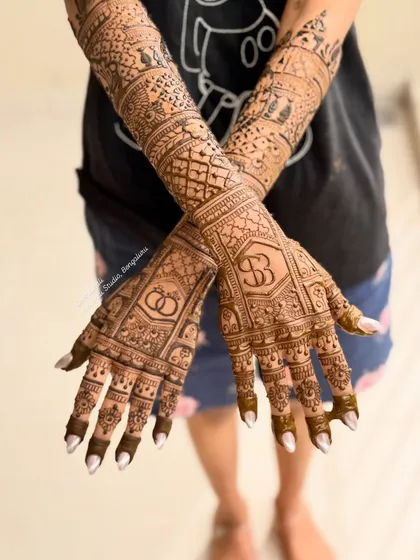 The back of the hands for Sheetal's engagement mehendi, featuring the couple's initials and interlocking rings.