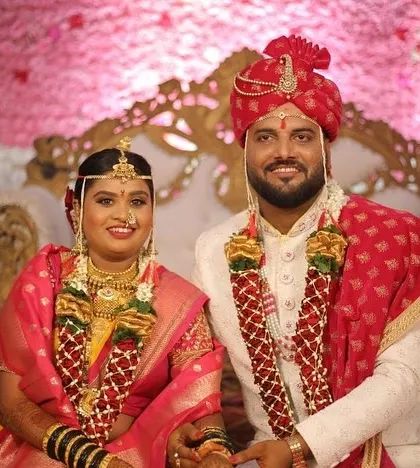A portrait of the Maharashtrian bride and groom. Her makeup is designed to complement the vibrant colors of her saree and the traditional gold jewelry.