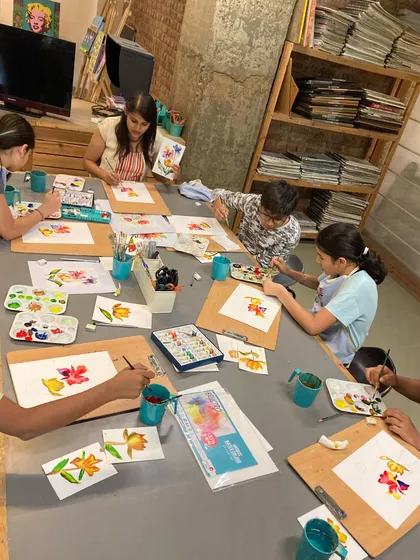 A class of adult students learning watercolor techniques, each practicing floral motifs on their boards.