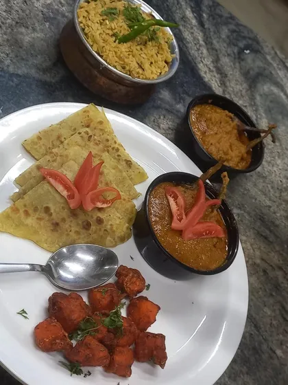 A complete and balanced North Indian meal, featuring soft parathas, a rich gravy, a dry vegetable side, and dal. This represents the wholesome and tasty daily lunch options we can provide for your team.