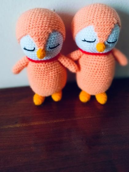 A pair of sweet, sleeping penguins in a soft orange color. They are about 6 inches tall.