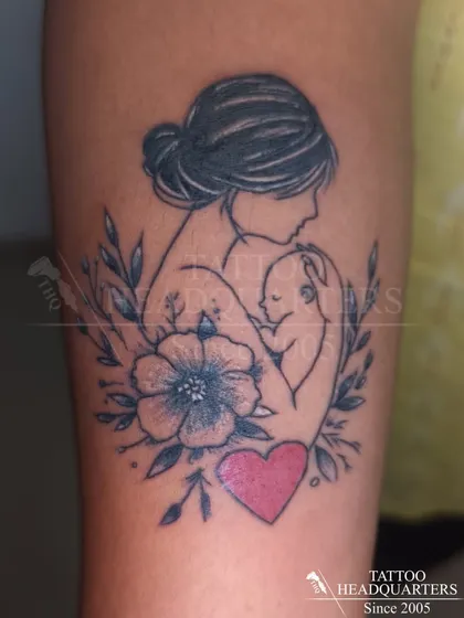 A touching tattoo of a mother holding her baby, surrounded by flowers, symbolizing the unbreakable bond of motherhood.