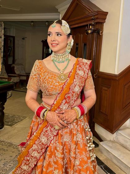 A full view of Anureet's beautiful orange bridal lehenga. The makeup is soft and complementary.