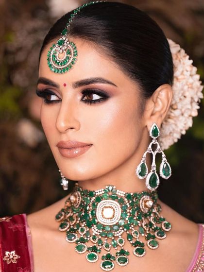 A close-up of a classic bridal look with a smokey eye. The rich emerald jewellery is the centerpiece, so the makeup is kept warm and defined to complement it perfectly.