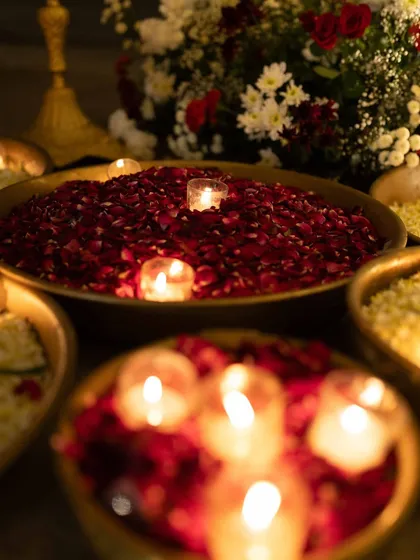 A close-up of the romantic Sangeet decor, with bowls of red rose petals and floating candles, creating a soft and intimate ambiance.