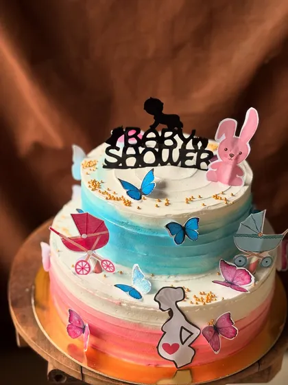 Another angle of the butterfly-themed baby shower cake, showing the different toppers like prams and a pregnant silhouette.