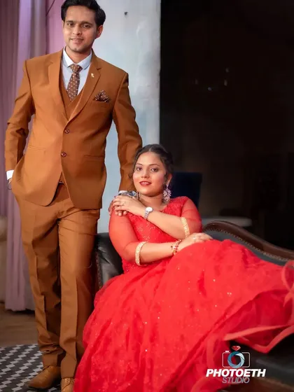 A classic and formal indoor portrait. The bride's flowing red gown and the groom's sharp suit create a look of elegance and sophistication.