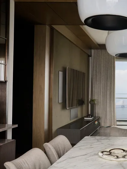 A detail of the living and dining area at 'Pad by the Bay,' showing how different zones are defined through furniture arrangement rather than walls. The television is integrated into a media unit that complements the room's warm, minimal aesthetic.