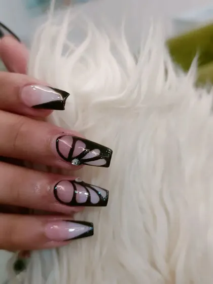 An elegant butterfly wing design on long coffin nails, using black line work on a sheer base with a single rhinestone accent.
