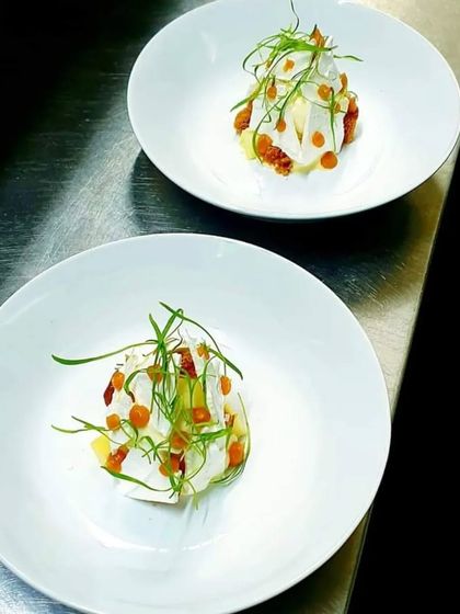 A light and airy dessert, possibly a meringue or foam, garnished with fresh herbs. An example of our experimental and modern dessert offerings.