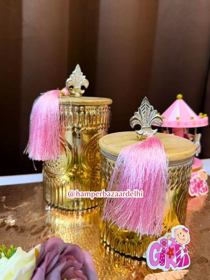 A close-up of the elegant golden jars with wooden lids and decorative tassels.