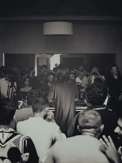 A black and white shot capturing the intimate, focused energy of the crowd gathered around the center stage for a mind-bending set by a guest artist.