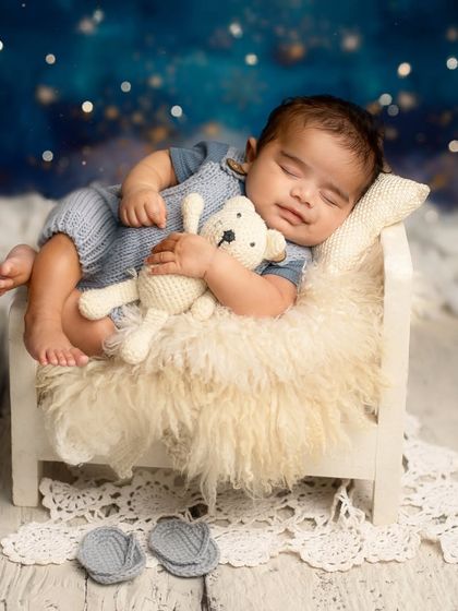 Dreaming among the stars. This setup features a tiny bed, a cuddly teddy bear, and a magical night sky backdrop for a truly dreamy portrait.