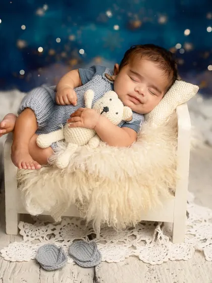 Dreaming among the stars. This setup features a tiny bed, a cuddly teddy bear, and a magical night sky backdrop for a truly dreamy portrait.
